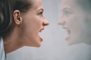 woman full of rage looking at self in mirror